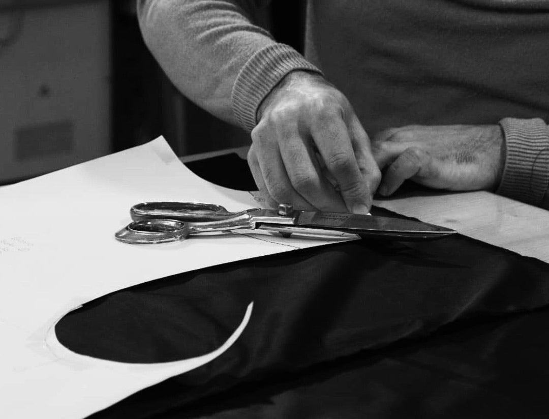 Aesthetic cinematic shot of high-quality wool fabric being cut by hand in a tailoring studio. Premium sustainable outerwear made in Germany by Spectrum Studios.