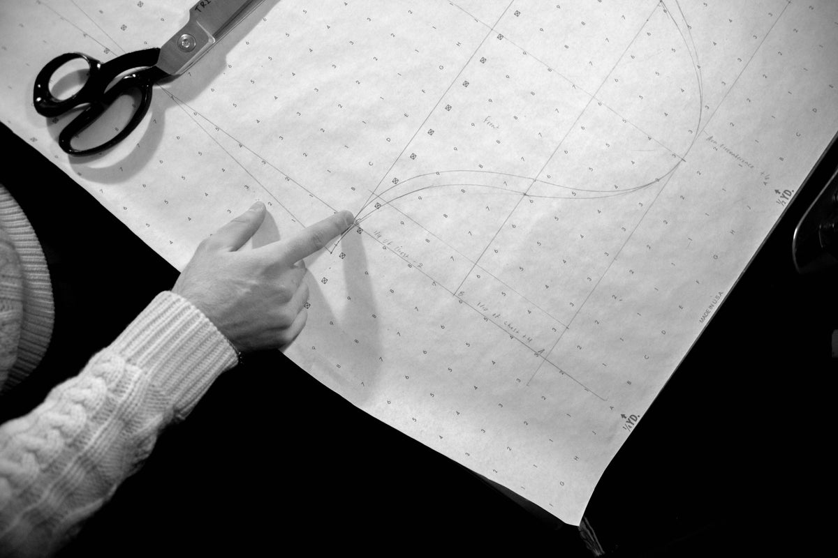 Artisan hands precisely cutting sustainable wool fabric on a large wooden table in a daylight tailoring studio. Authentic German fashion craftsmanship.